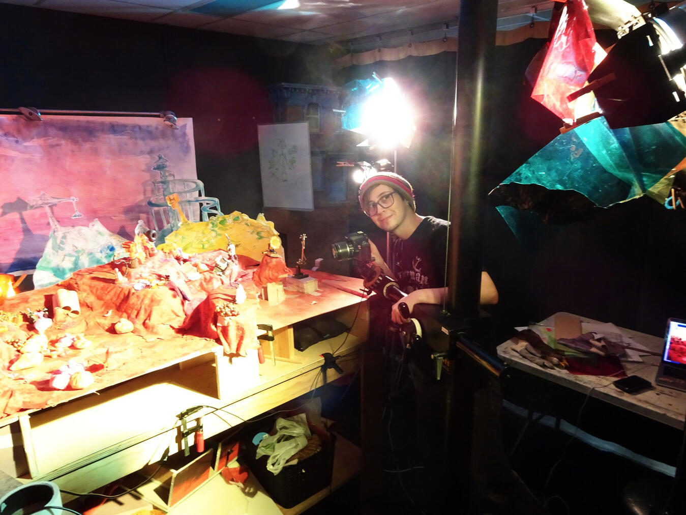 A photo of the studio space that the stop-motion film SWAP was created in. The animator Elliot Maxted is setting up the camera and lights to film a scene.