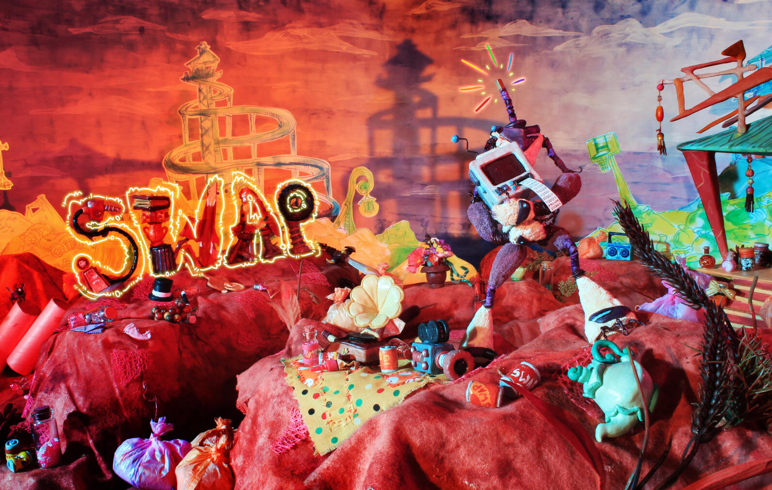 A promotional poster for a stop-motion film. Set in a colourful junkyard, the word 'SWAP' is written in sculpted trash. A headless robot named Servo is in the foreground, holding a broken computer monitor.