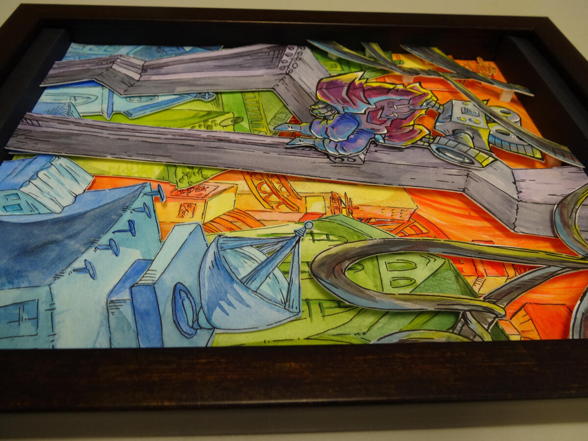 A photo of a colourful shadowbox. It depicts a robot with a camera for a head sitting atop a construction beam and watching over a city.