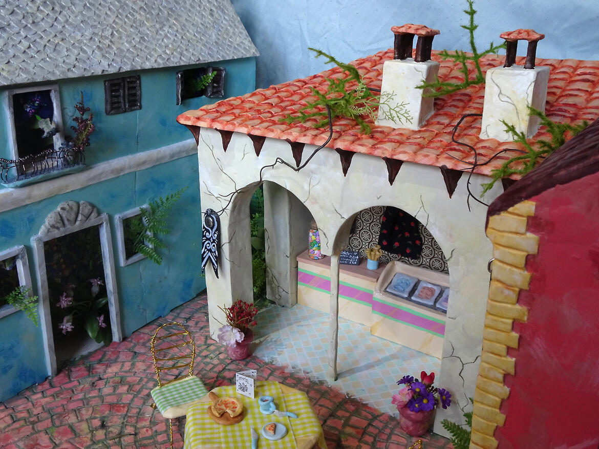 A photo of miniature buildings, made to look like a small gelato street in Italy.