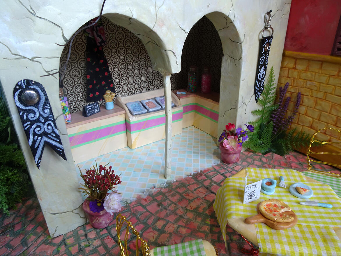A photo of miniature buildings, made to look like a small gelato street in Italy.