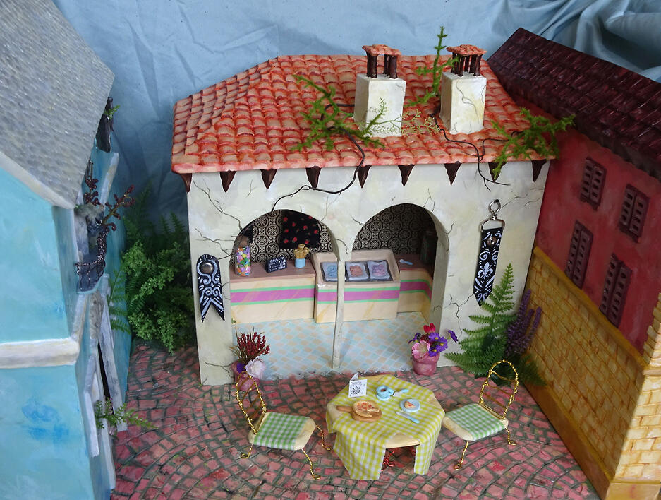 A photo of miniature buildings, made to look like a small gelato street in Italy.